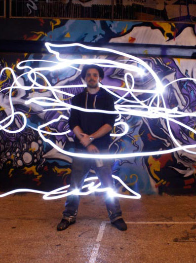 kanos is standing and a light painting is around him, in background his graffiti in molitor piscine