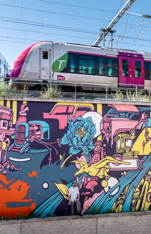 projet horizon paris , alex kanos stand on with a graffiti wall painted in background and above there is a railroad with a train